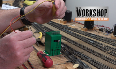 Hands working over an unfinished model railroad.